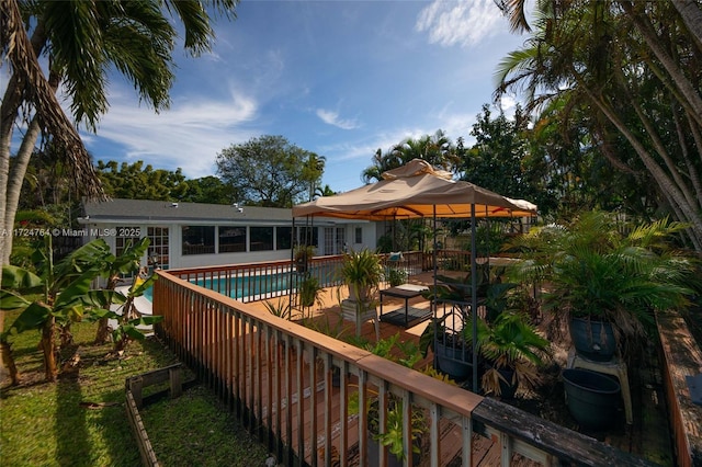 wooden terrace with a fenced in pool and a sunroom