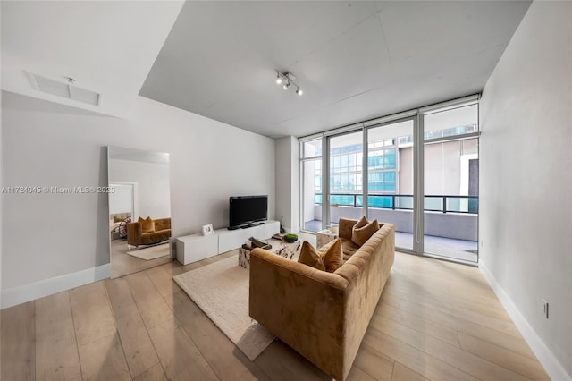 living room featuring rail lighting, light hardwood / wood-style floors, and expansive windows