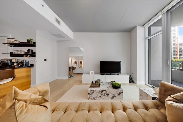 living room featuring light wood-type flooring and a wall of windows