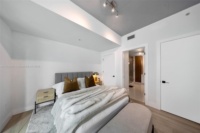 bedroom with light wood-type flooring and connected bathroom