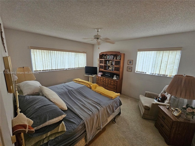 bedroom with ceiling fan, light colored carpet, and a textured ceiling