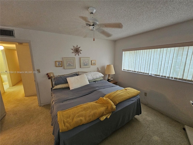 carpeted bedroom with ceiling fan, a textured ceiling, and connected bathroom