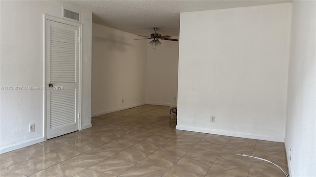 spare room featuring ceiling fan, light tile patterned floors, and a textured ceiling