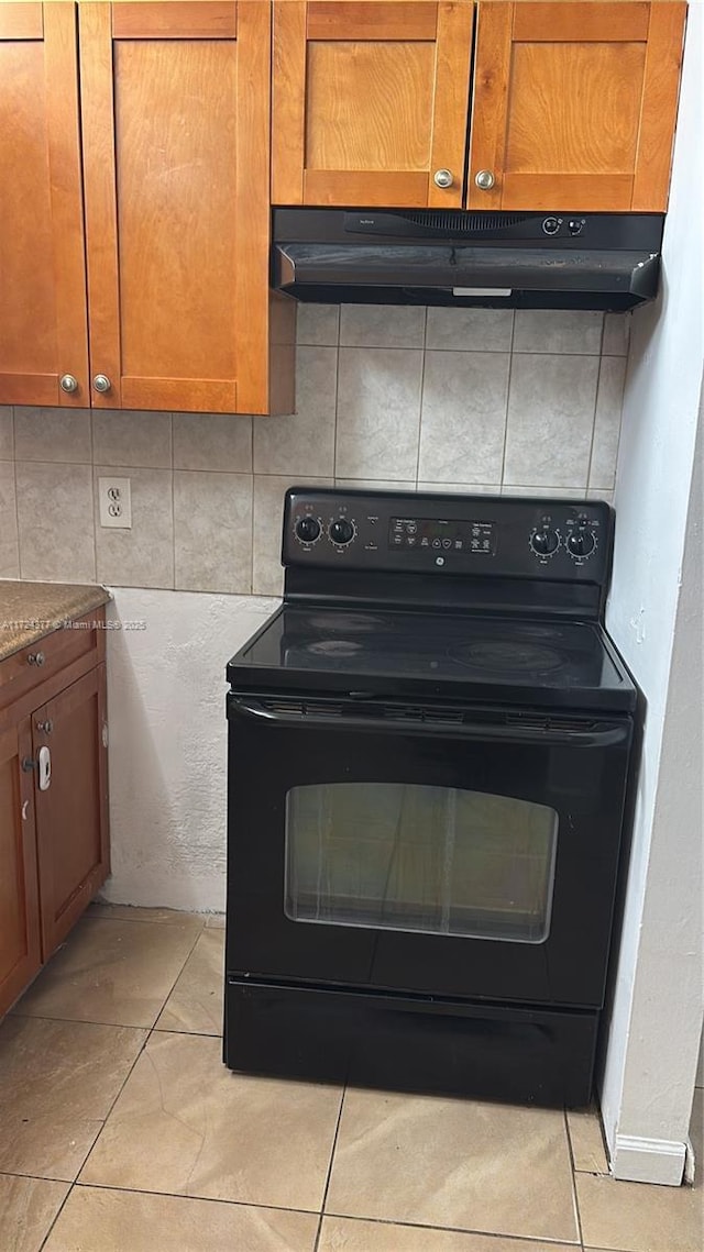 kitchen with decorative backsplash, light stone countertops, black range with electric stovetop, and light tile patterned floors