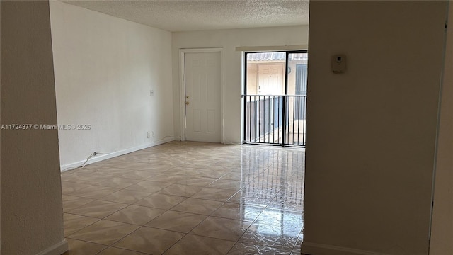 empty room with a textured ceiling and light tile patterned flooring