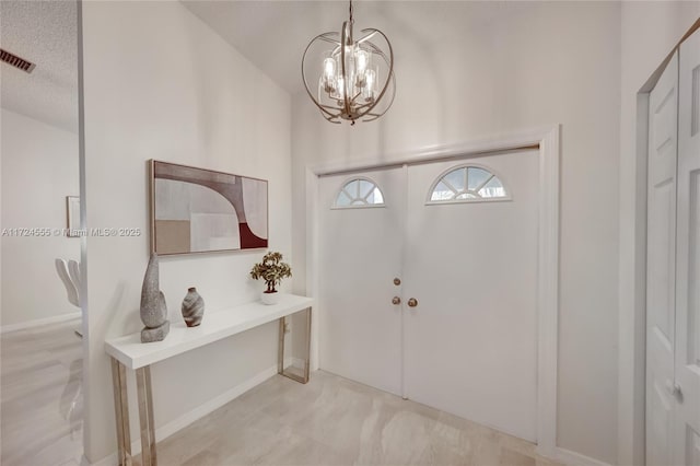 foyer entrance with a chandelier and visible vents