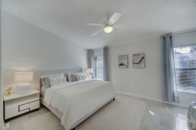 bedroom with ceiling fan, lofted ceiling, baseboards, and a textured ceiling