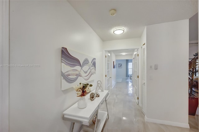 corridor featuring a textured ceiling and baseboards