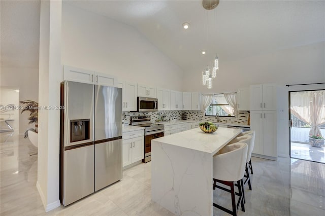 kitchen featuring pendant lighting, a sink, backsplash, a center island, and stainless steel appliances