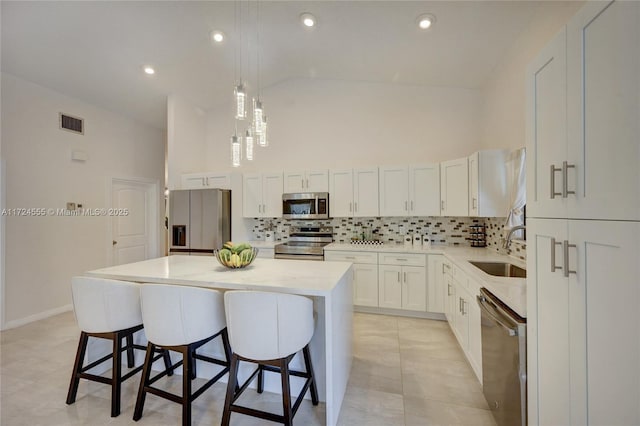 kitchen featuring visible vents, a sink, backsplash, a center island, and appliances with stainless steel finishes