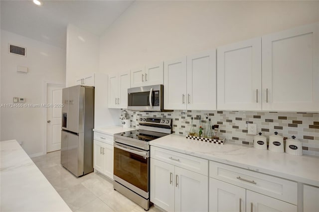 kitchen featuring tasteful backsplash, visible vents, light stone countertops, white cabinets, and stainless steel appliances