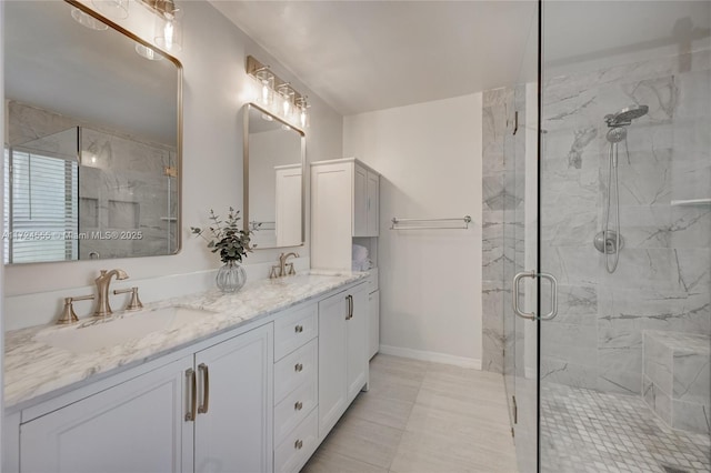 bathroom with a sink, a marble finish shower, and double vanity