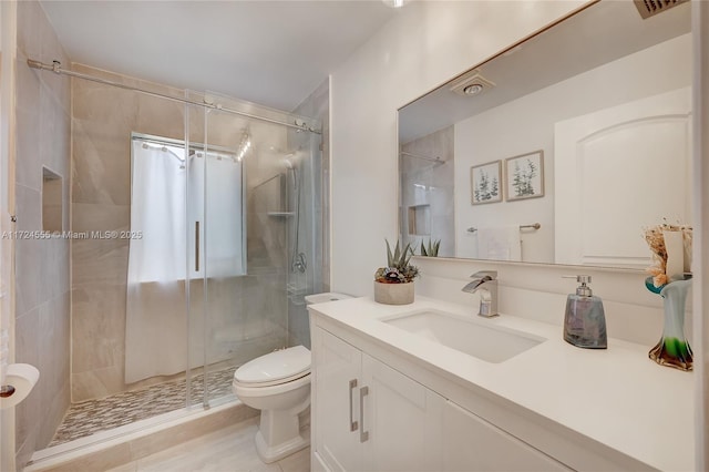 bathroom featuring vanity, a shower stall, and toilet