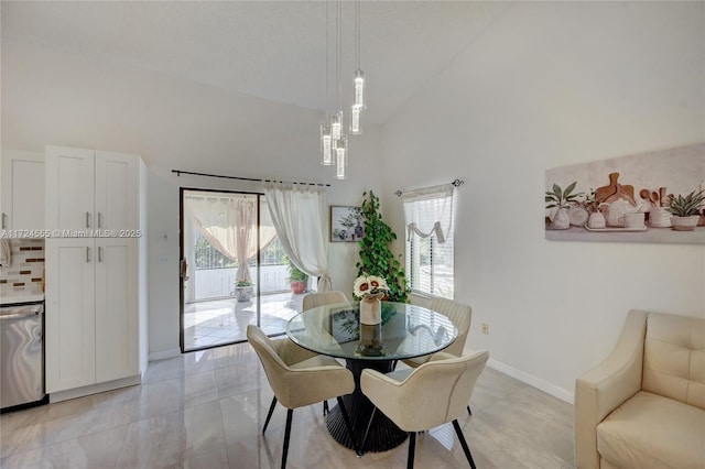 dining room with light tile patterned floors, baseboards, and high vaulted ceiling