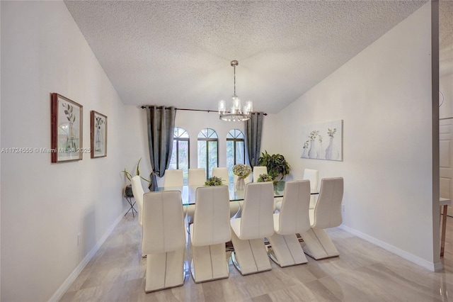 dining space with baseboards, a textured ceiling, a chandelier, and vaulted ceiling