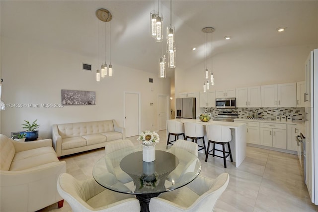 living room with light tile patterned floors, visible vents, and high vaulted ceiling