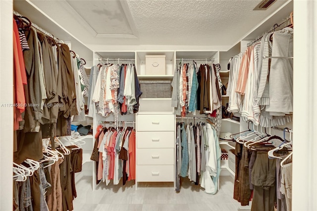 walk in closet with tile patterned floors, visible vents, and attic access