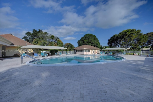 community pool with a patio area and fence