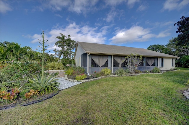 rear view of property featuring a lawn, a sunroom, and stucco siding