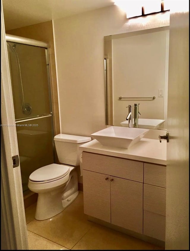 bathroom with tile patterned floors, vanity, toilet, and an enclosed shower