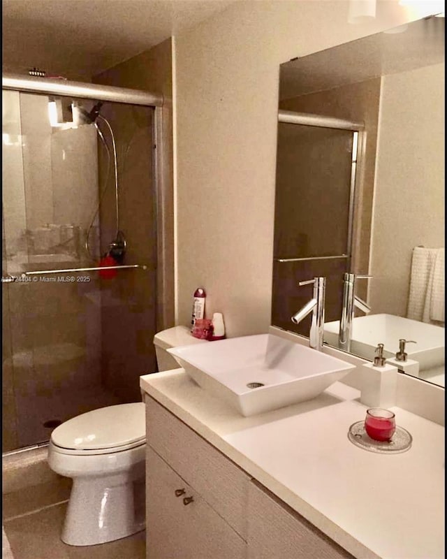 bathroom featuring vanity, toilet, and a shower with shower door