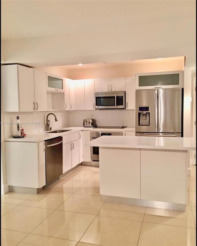 kitchen with white cabinets, light tile patterned flooring, sink, and stainless steel appliances