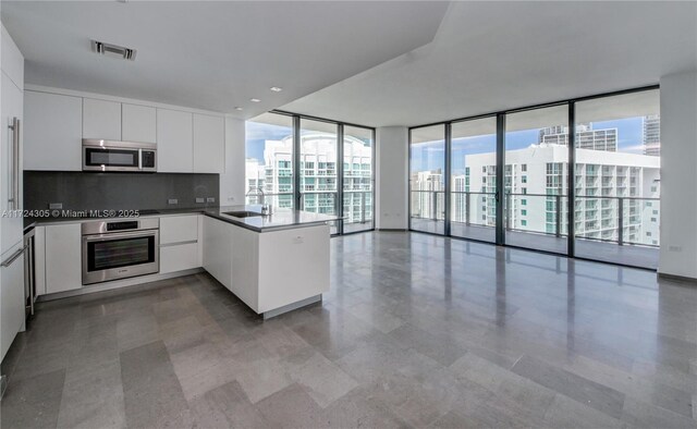 kitchen featuring visible vents, modern cabinets, expansive windows, stainless steel appliances, and a peninsula