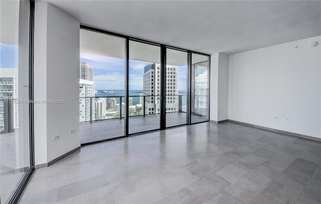 unfurnished room with a wall of windows, a view of city, and baseboards