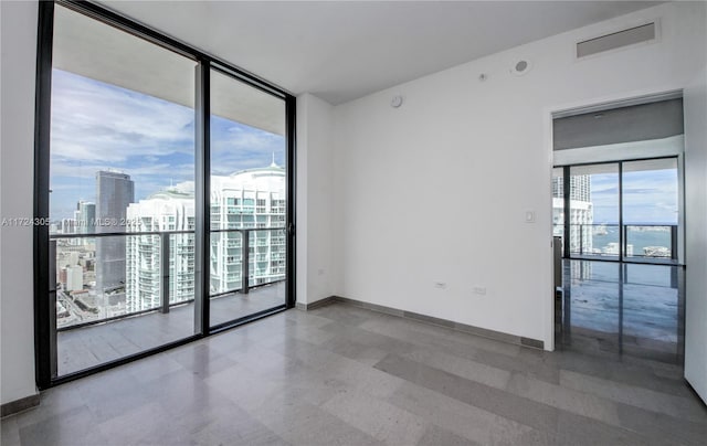 unfurnished room featuring visible vents, baseboards, floor to ceiling windows, tile patterned floors, and a view of city