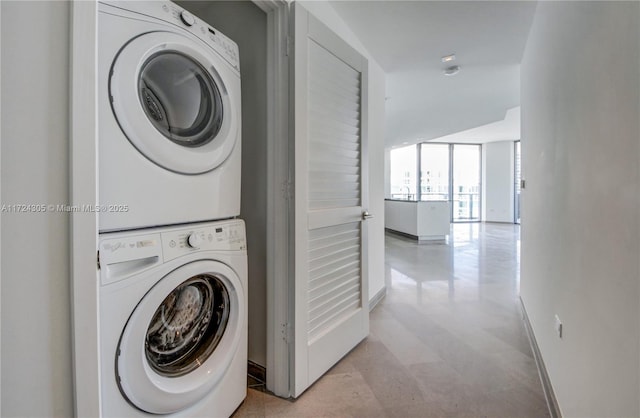 clothes washing area featuring baseboards, laundry area, and stacked washer / dryer