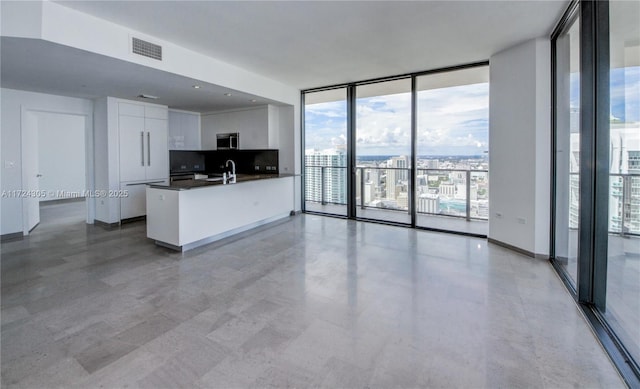 kitchen featuring visible vents, a sink, floor to ceiling windows, dark countertops, and stainless steel microwave