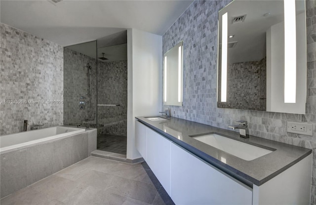 bathroom featuring visible vents, a shower stall, a bath, tile walls, and a sink