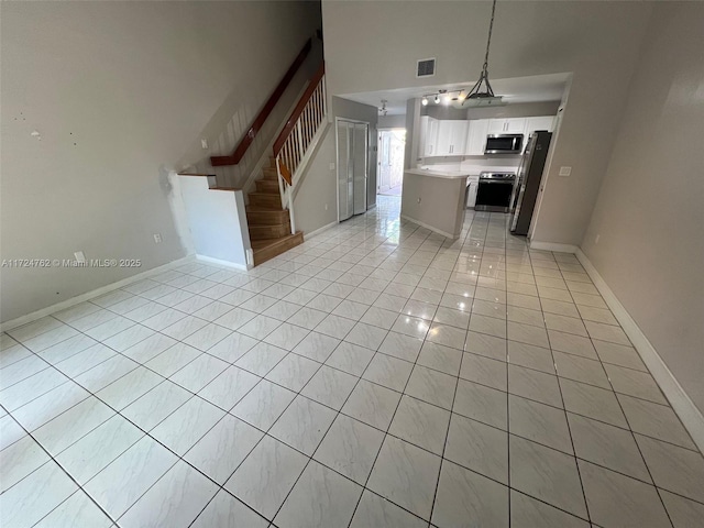 kitchen with light countertops, appliances with stainless steel finishes, open floor plan, light tile patterned flooring, and white cabinetry