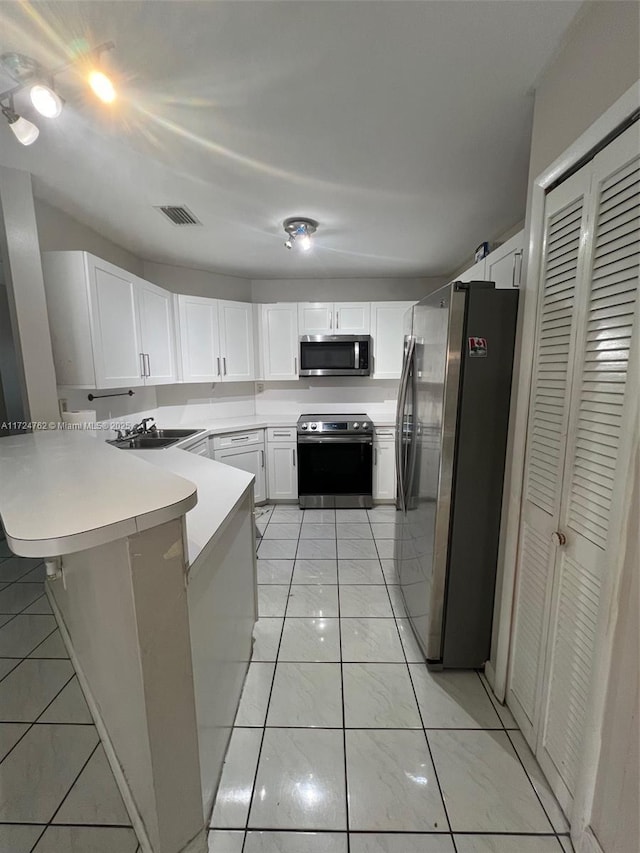 kitchen with appliances with stainless steel finishes, visible vents, a peninsula, and white cabinetry