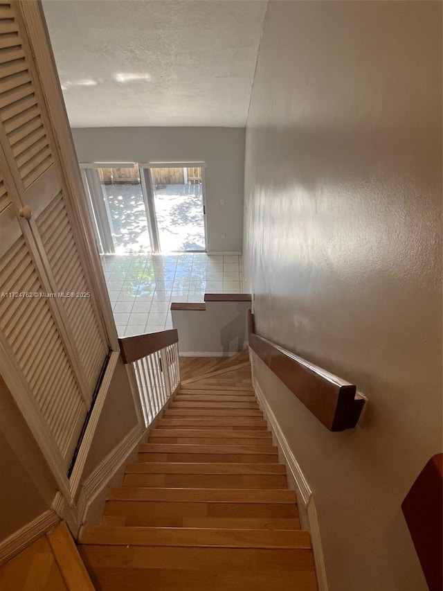 stairway featuring a textured ceiling and wood finished floors