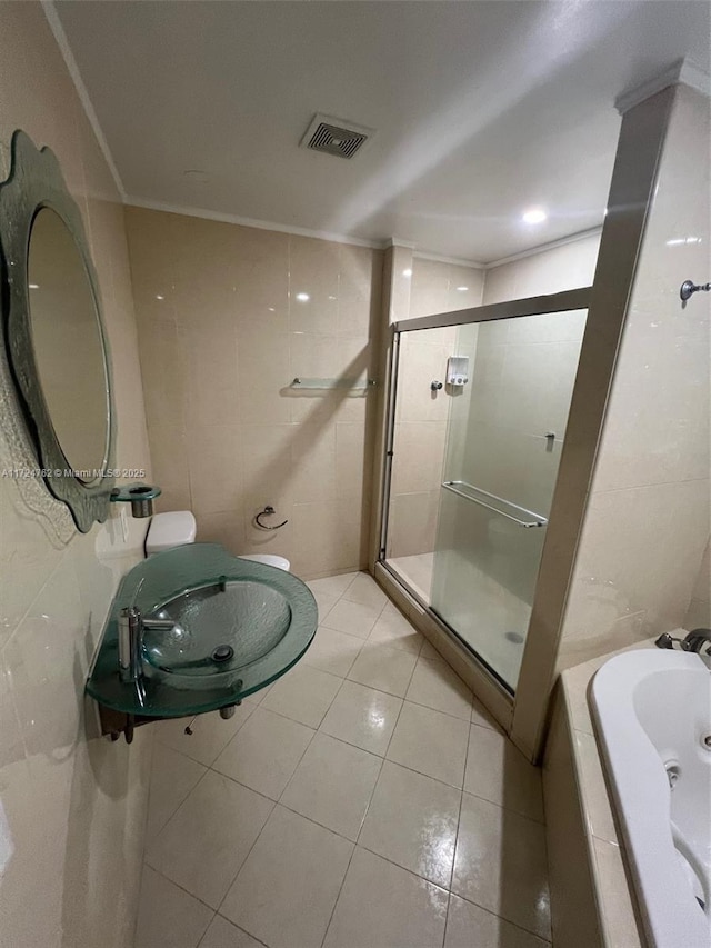 bathroom with visible vents, tile walls, tile patterned flooring, a shower stall, and a sink