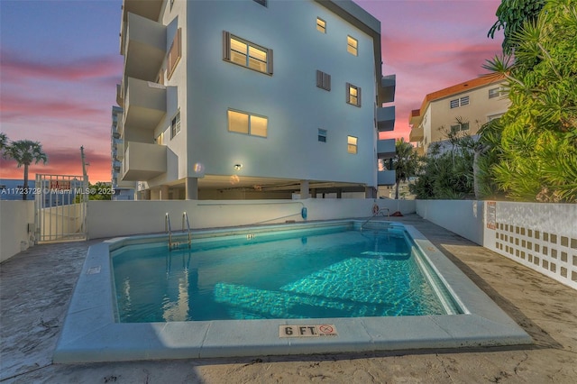 back of property featuring a community pool, fence, a gate, and stucco siding