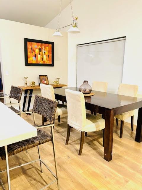 dining area with light wood-type flooring and vaulted ceiling