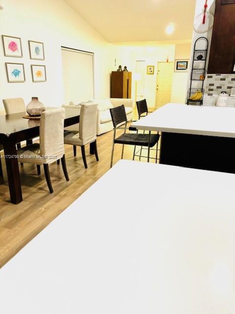 dining space with light wood-type flooring and vaulted ceiling