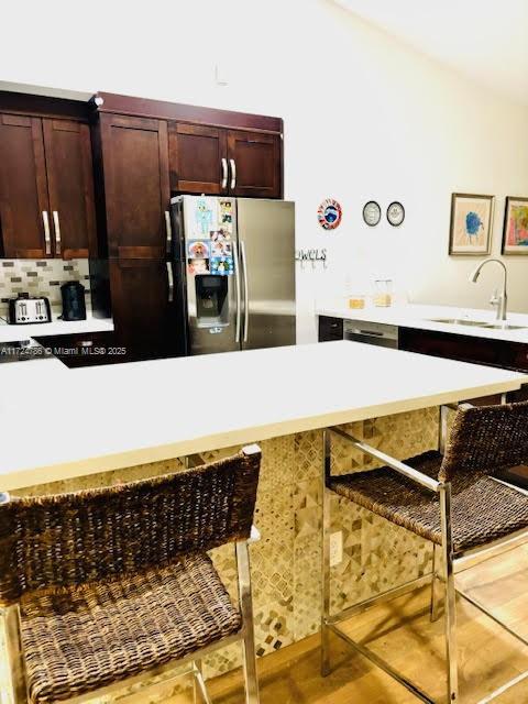 4357 Magnolia Ridge Dr, Weston, FL 33331 - kitchen with stainless steel fridge with ice dispenser, a kitchen bar, a sink, light countertops, and lofted ceiling