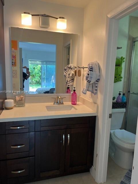 full bath with toilet, a shower stall, vanity, and tile patterned flooring