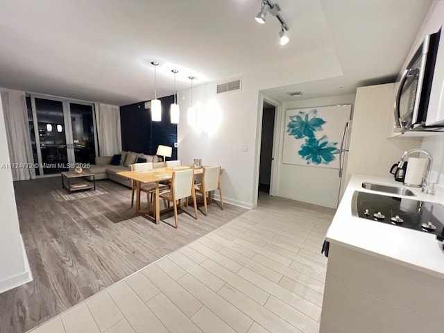 kitchen featuring sink, light hardwood / wood-style flooring, hanging light fixtures, and black electric stovetop