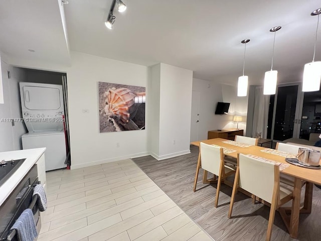 kitchen featuring light hardwood / wood-style floors, hanging light fixtures, and stacked washer and clothes dryer