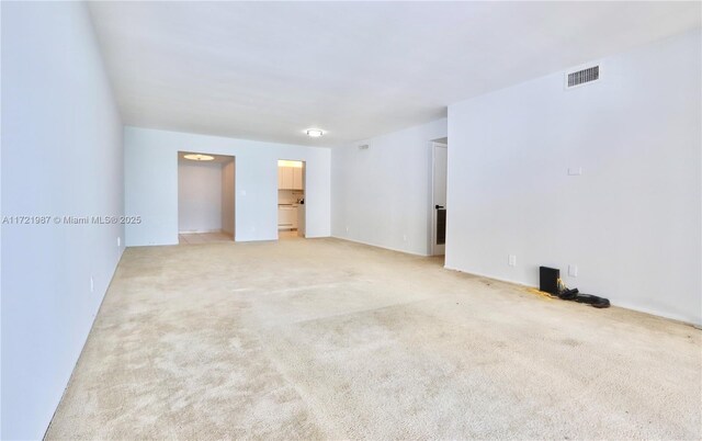 spare room with a wall of windows and light carpet