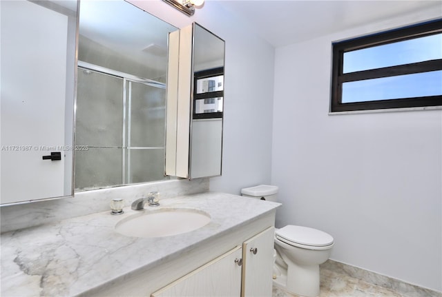 bathroom with vanity, toilet, and a shower with door