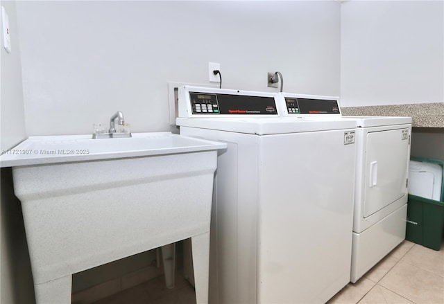 laundry area with sink, light tile patterned floors, and washer and dryer