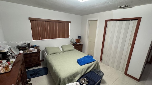 tiled bedroom with a closet and visible vents