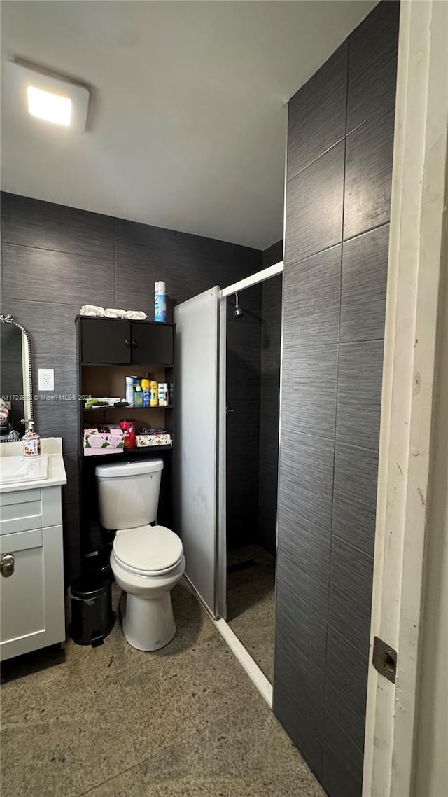 full bathroom with toilet, a shower stall, tile walls, and vanity