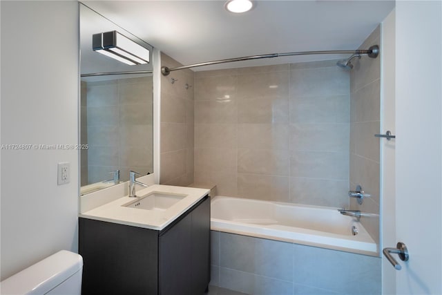 bathroom featuring toilet, tiled shower / bath, and vanity