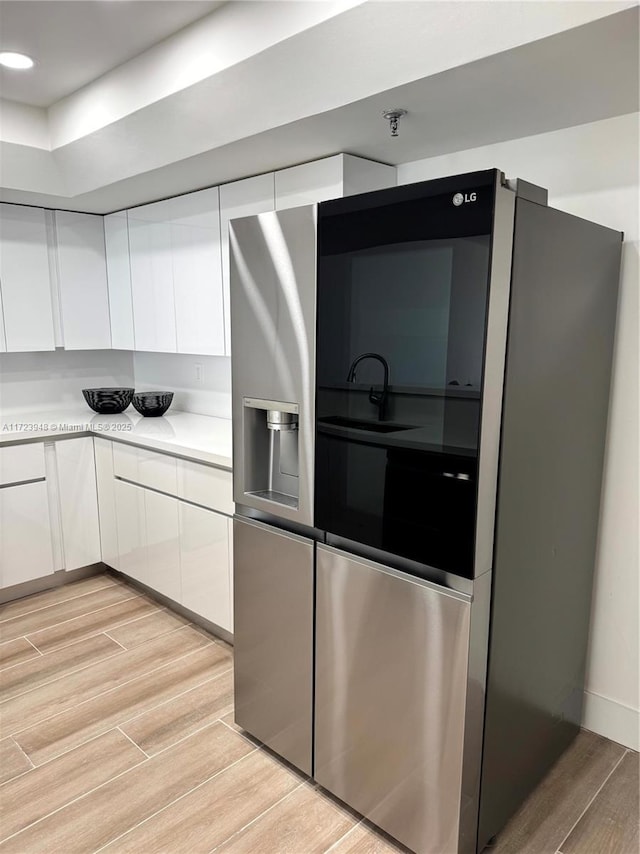 kitchen with stainless steel fridge with ice dispenser and white cabinetry